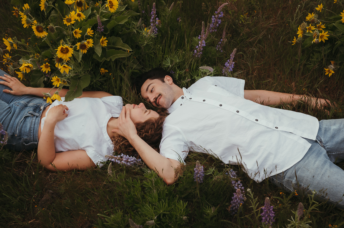 Intimate couple laying together near wildflowers