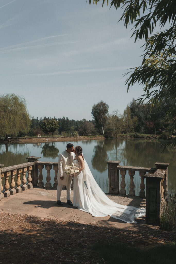 Bride and groom kissing in front of stone archway at Villa Catalana Cellars