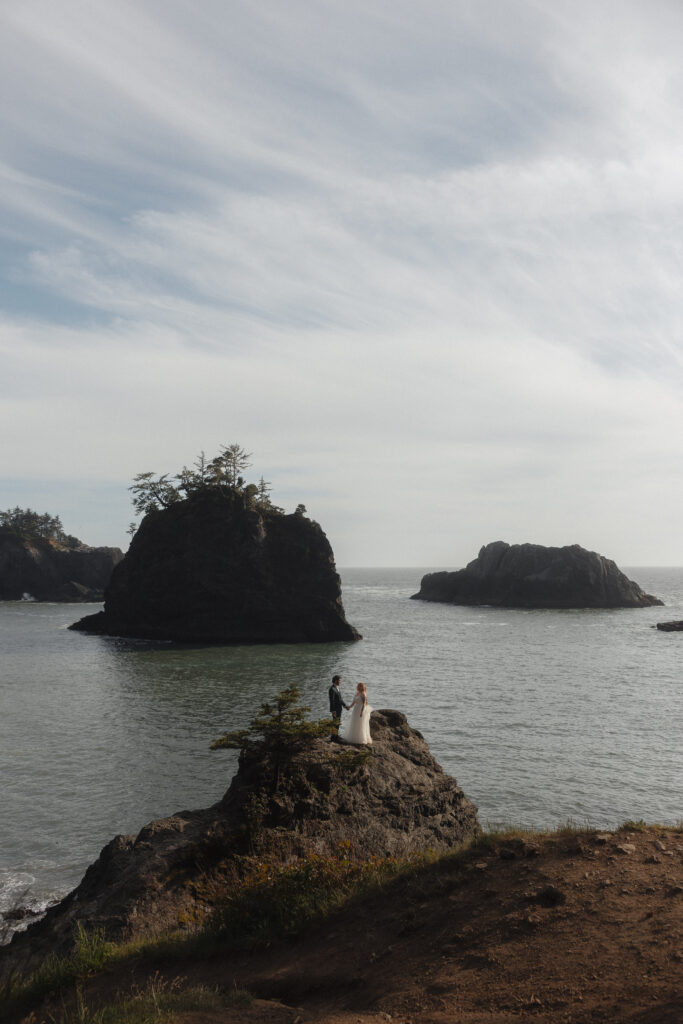 Elopement couple exploring the rock bluffs at Secret Beach in Brookings, OR