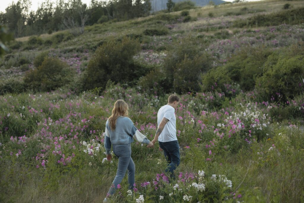 Captured by their Washington engagement photographer, a couple walks along the Columbia River in the Gorge