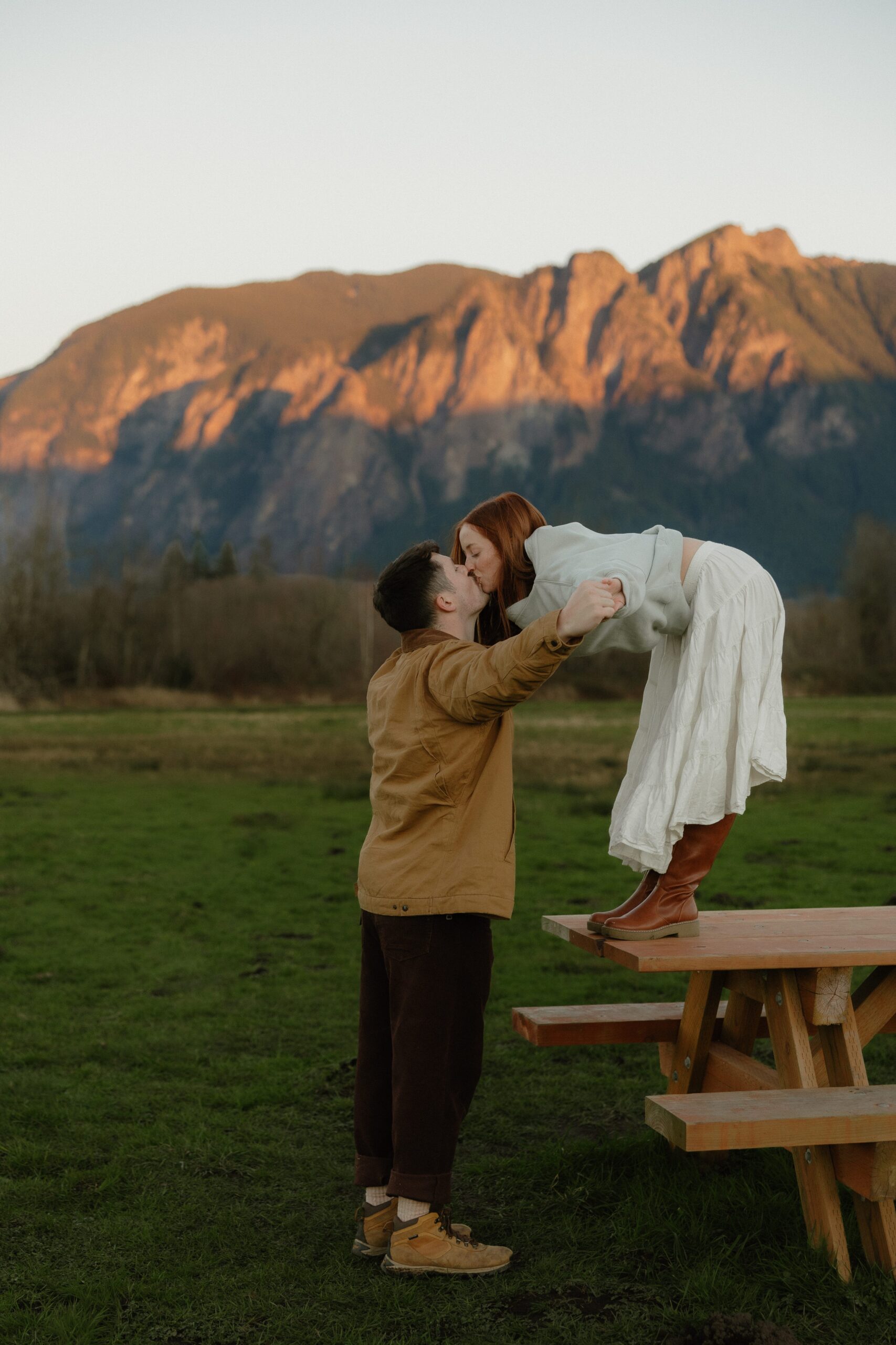 Candid engagement photos at Elk Fields with soft grasses and mountain views