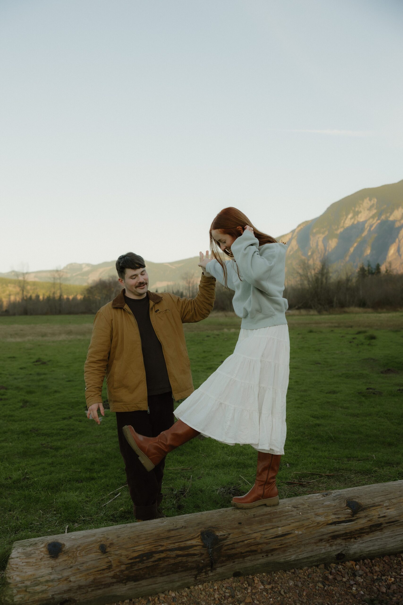 Candid engagement photos at Elk Fields with soft grasses and mountain views
