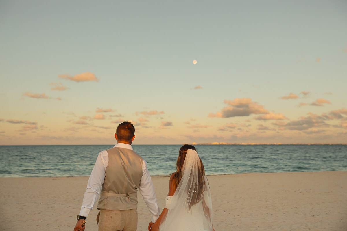 Wedding couple walking along the beach of Cancún, Mexico.