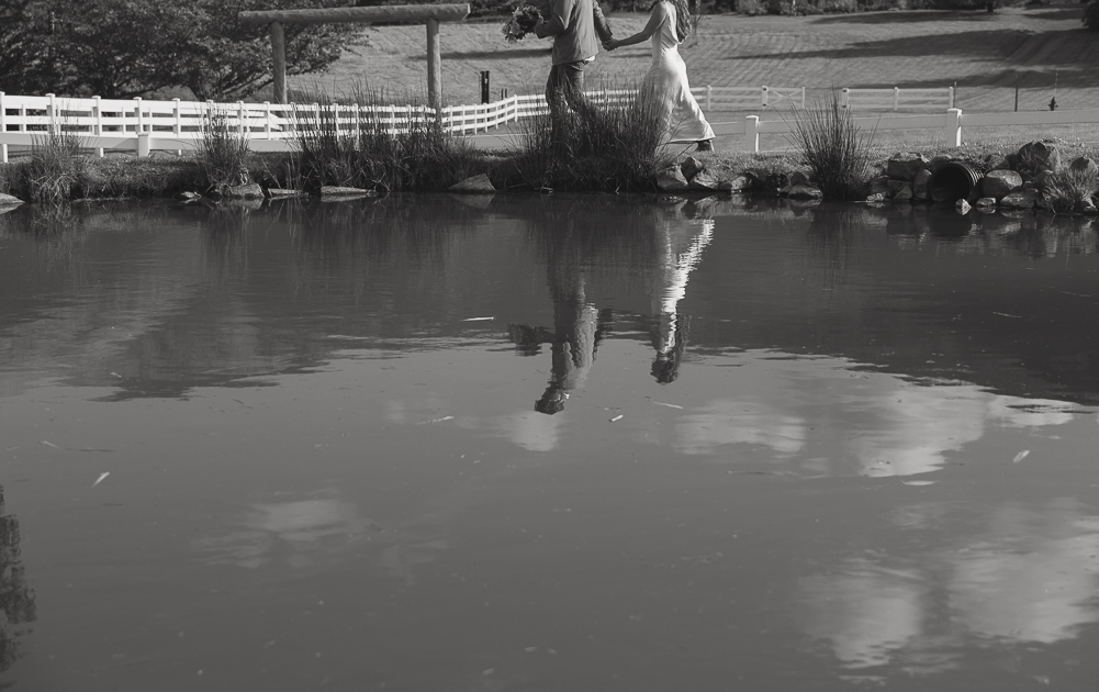 Reflection of an elopement couple around the lily pond at Wind Mountain Ranch.