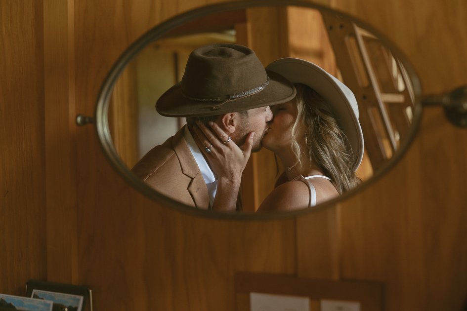 A wedding couple share a kiss inside the cabin at Wind Mountain Ranch.