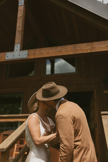 A wedding couple share a kiss outside the cabin at Wind Mountain Ranch.