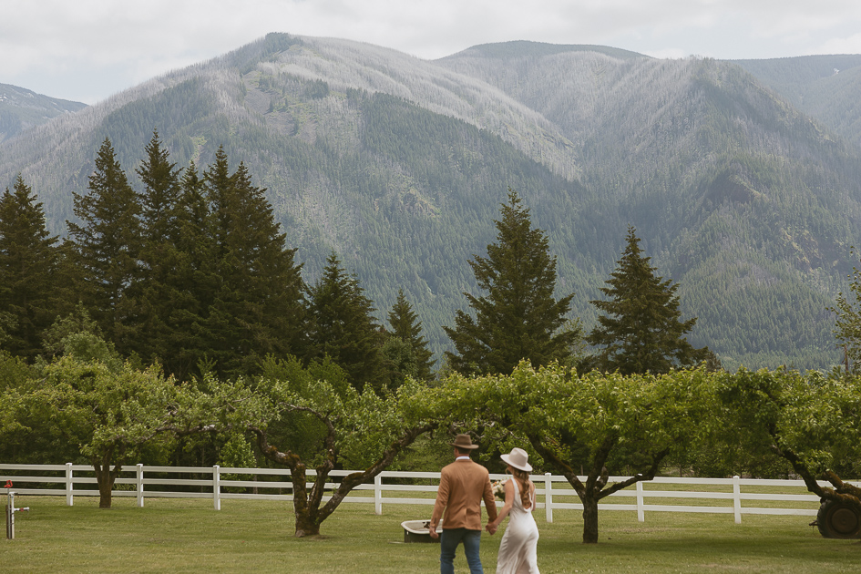 Married couple walking through the orchard at Wind Mountain Ranch.